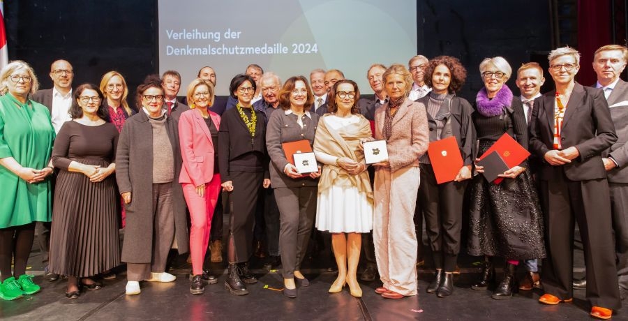 Gruppenbild der Preisträger:innen der Denkmalschutzmedaille auf der Kino-Bühne